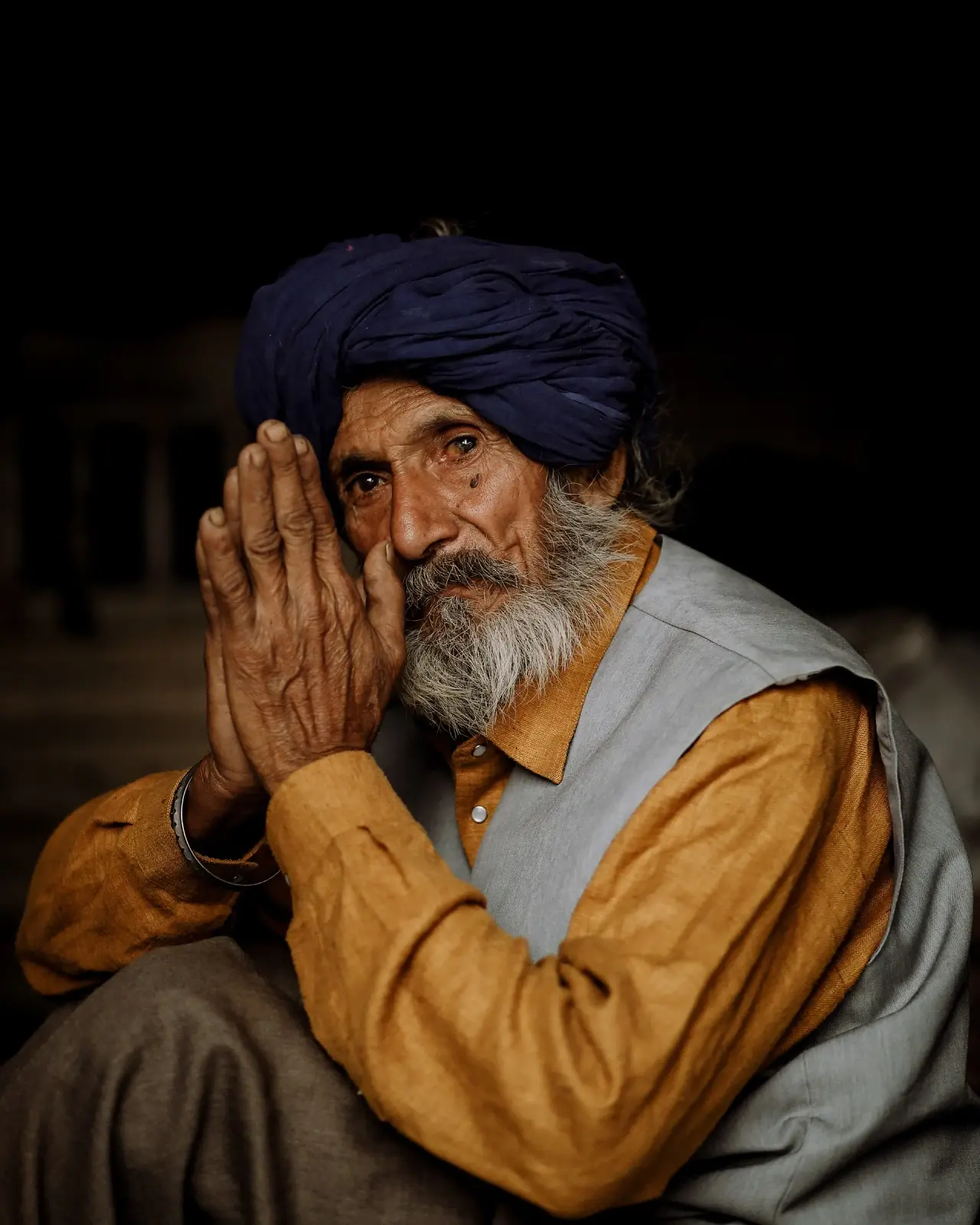 An elderly man with folded hands