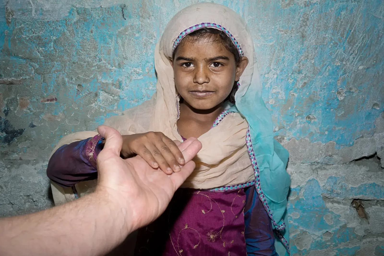 A hand reaching out to a young girl