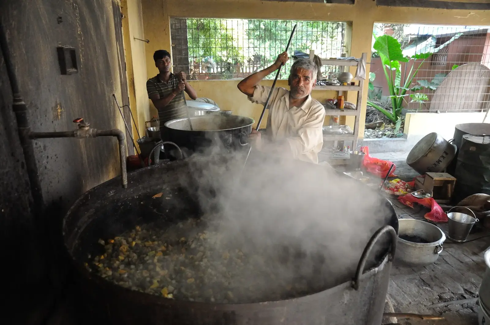A volunteer stirring a large pot in a community kitchen